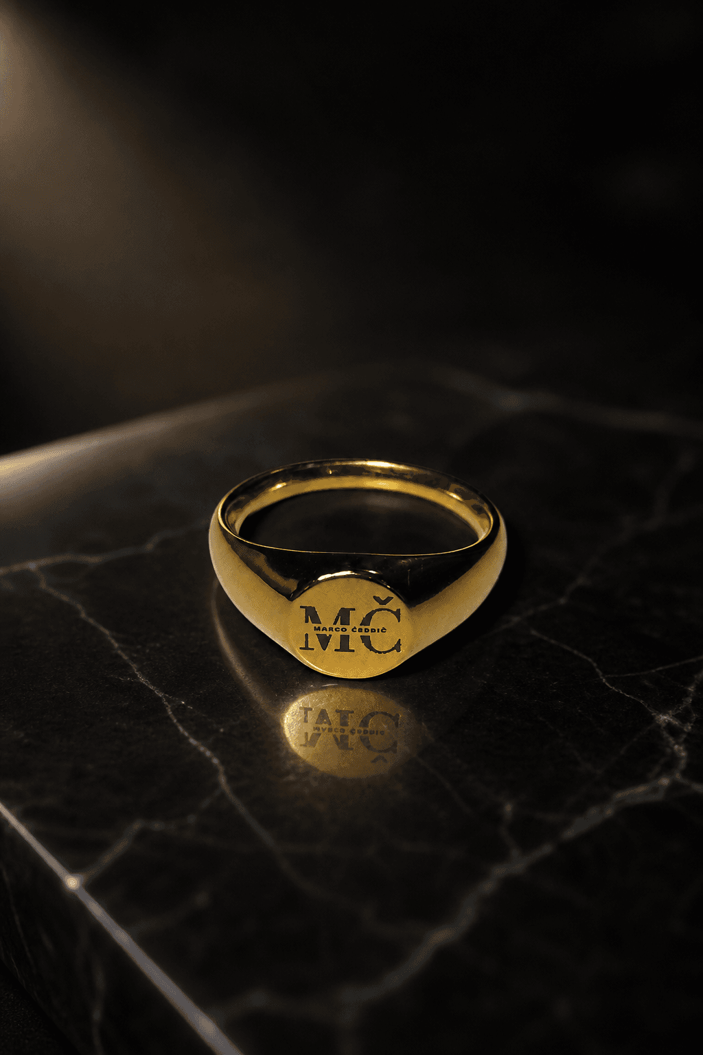 Gold MČ ring on black studio background